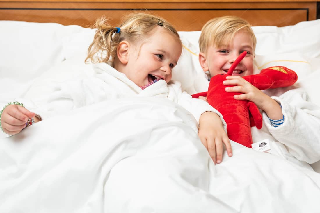 kids in bed playing with lobster doll